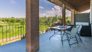 Une terrasse extérieure avec un pilier en briques, une table avec des chaises et un barbecue.