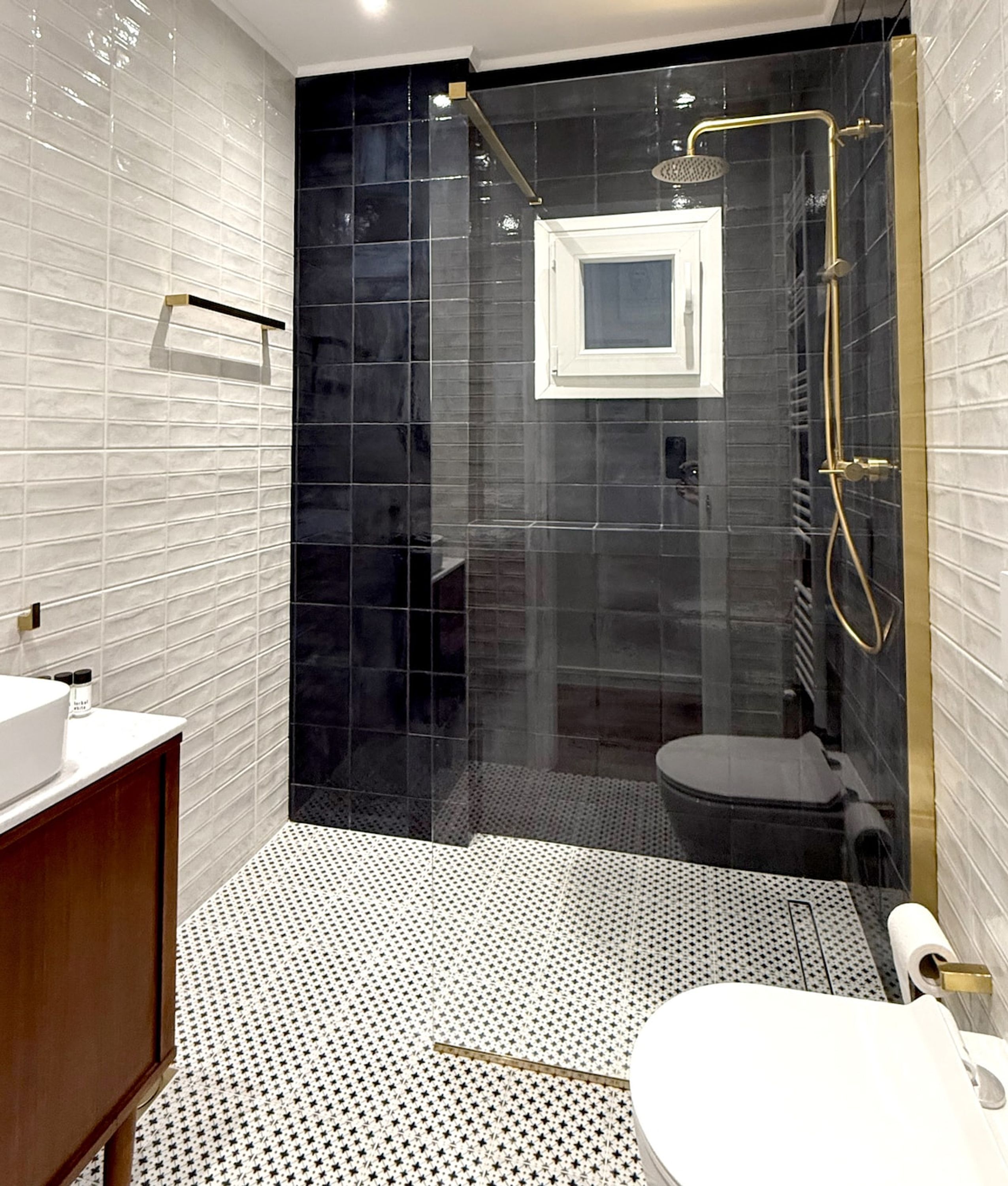 Un bany modern amb dutxa de vidre, un lavabo blanc i un vàter.