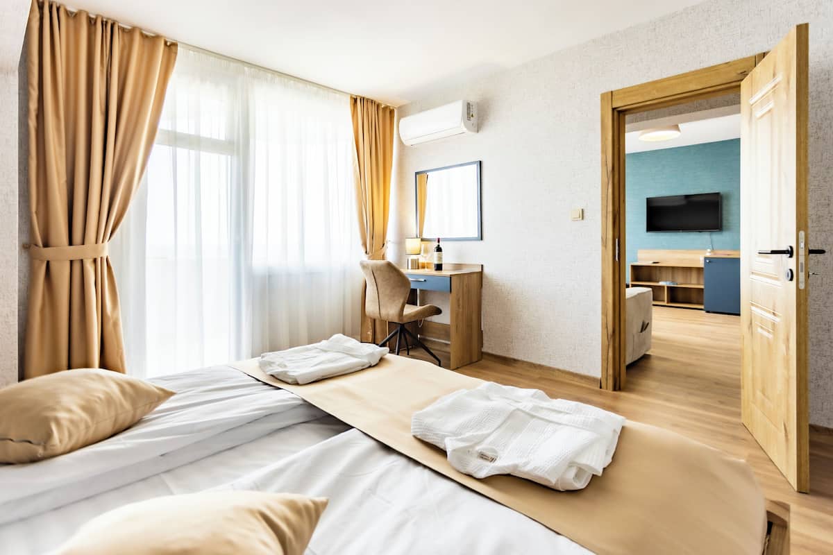 A hotel room with a bed, a desk, a chair, and a television.