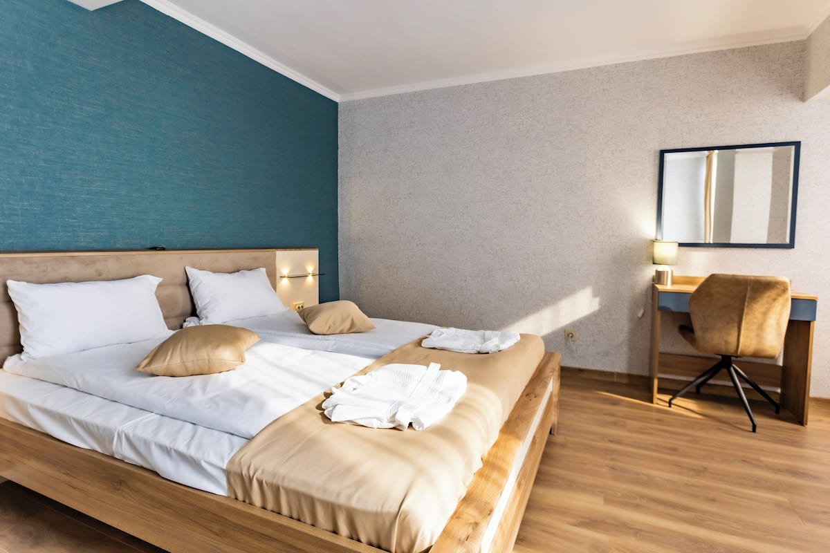 A modern hotel room with a large bed, a desk, and a chair.