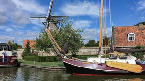 A traditional sailing boat docked at a canal with a windmill in the background. - Gorgeous home in Lemmer with WiFi (Lemmer)