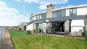 A modern house with a large glass door, a deck, and a view of the water. - Gorgeous home in Lemmer with WiFi (Lemmer)
