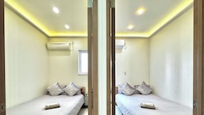 Quarto com espelhos, duas camas, uma janela e iluminação no teto.