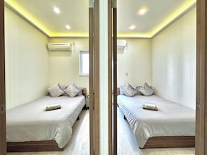 A mirrored room with two beds, a window, and ceiling lights.