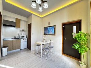 A compact kitchen with modern appliances, a dining area with a table and stools, a television mounted on the wall, and a door with a potted plant beside it. - Tongtian阁 for 3 minutes! 1 minute from the station! Close to Heimen Shichiba场难波! (Nipponbashi, Naniwa Ward,6F,Osaka)