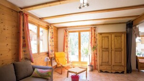 A cozy room with a wooden interior, a sofa, a chair, a table with magazines, and a large wardrobe. - L'Echaillon - Soldanelle (Névache)