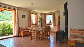 Um quarto espaçoso com uma mesa de jantar e cadeiras, um sofá e uma janela grande com cortinas.