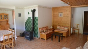 Um quarto aconchegante com uma lareira de madeira, uma mesa de jantar com cadeiras, um sofá e um armário de madeira.
