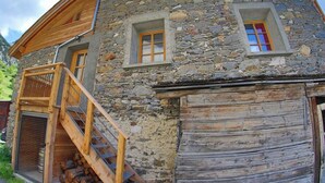 Ein Steinhaus mit einer Holztreppe, die zu einem überdachten Bereich führt.