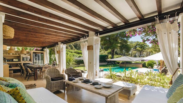 Un espacio al aire libre cubierto con piscina, mobiliario de mimbre y zona de comedor.