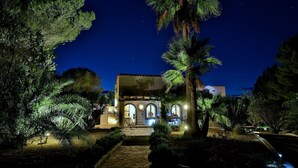 Un edificio bien iluminado con ventanas de arco y un sendero de piedra que conduce a la entrada.