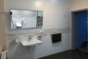 A modern bathroom with a white sink, a mirror, and a towel hanging on the wall. - Resort Dreistern, Pension Resort Dreister - DZ 01 (barrierefrei) (Göda)