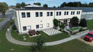 Un bâtiment à deux étages, doté d’un toit plat, d’un espace extérieur couvert aménagé en coin salon et d’une allée pavée.