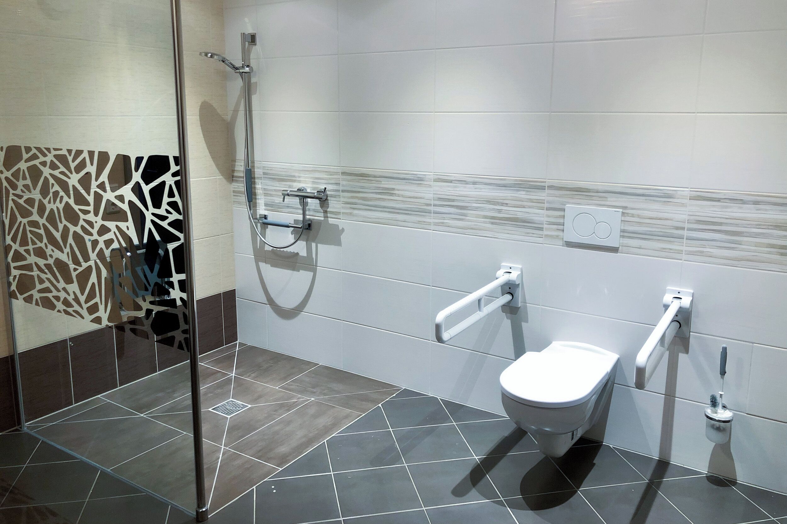 Un baño moderno con cabina de ducha de vidrio, inodoro blanco y barra de apoyo.