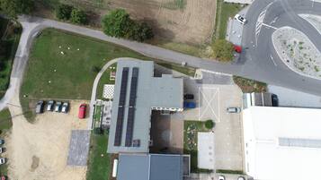 An aerial view of a building with a parking lot, solar panels, and a road intersection.