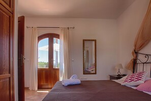 A bedroom with a bed, a nightstand, a mirror, and a view through a door.
