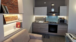 A compact kitchen with a gas stove, microwave, and modern cabinetry. - Casa Belfiore - Martiri di Belfiore 23 (Vicenza)