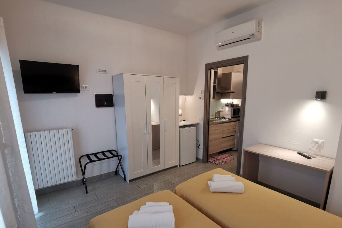 Ein Hotelzimmer mit zwei Betten, einer Küchenzeile, einem Fernseher und einer Klimaanlage.