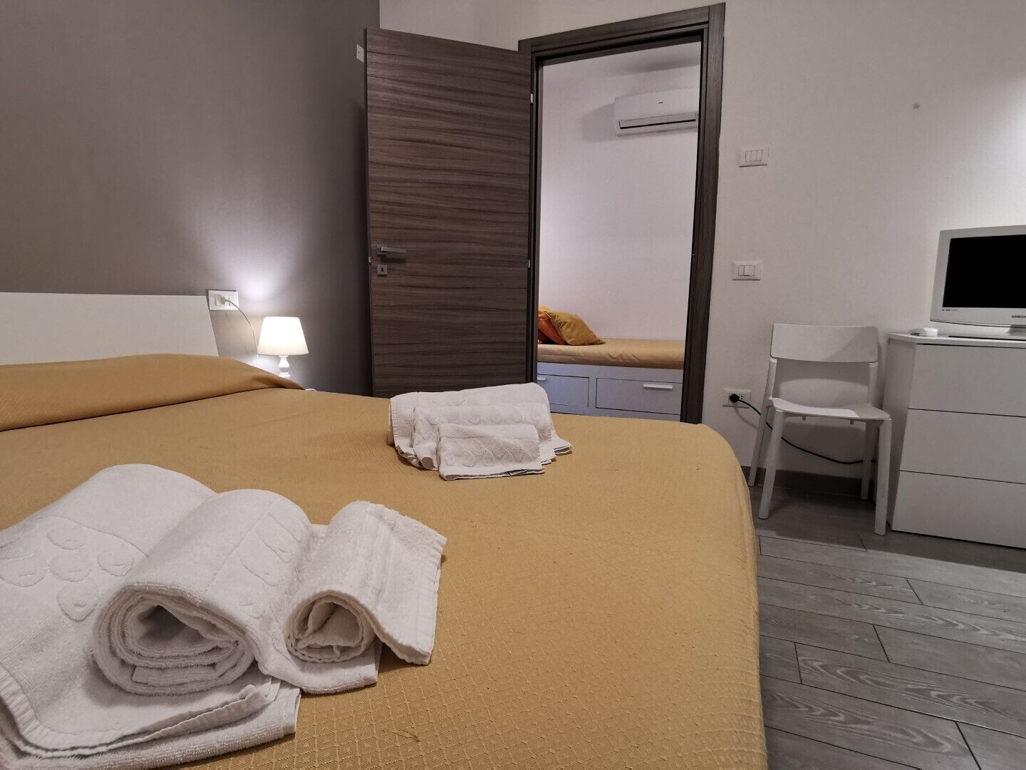 A hotel room with a bed, a desk, a chair, and a television.