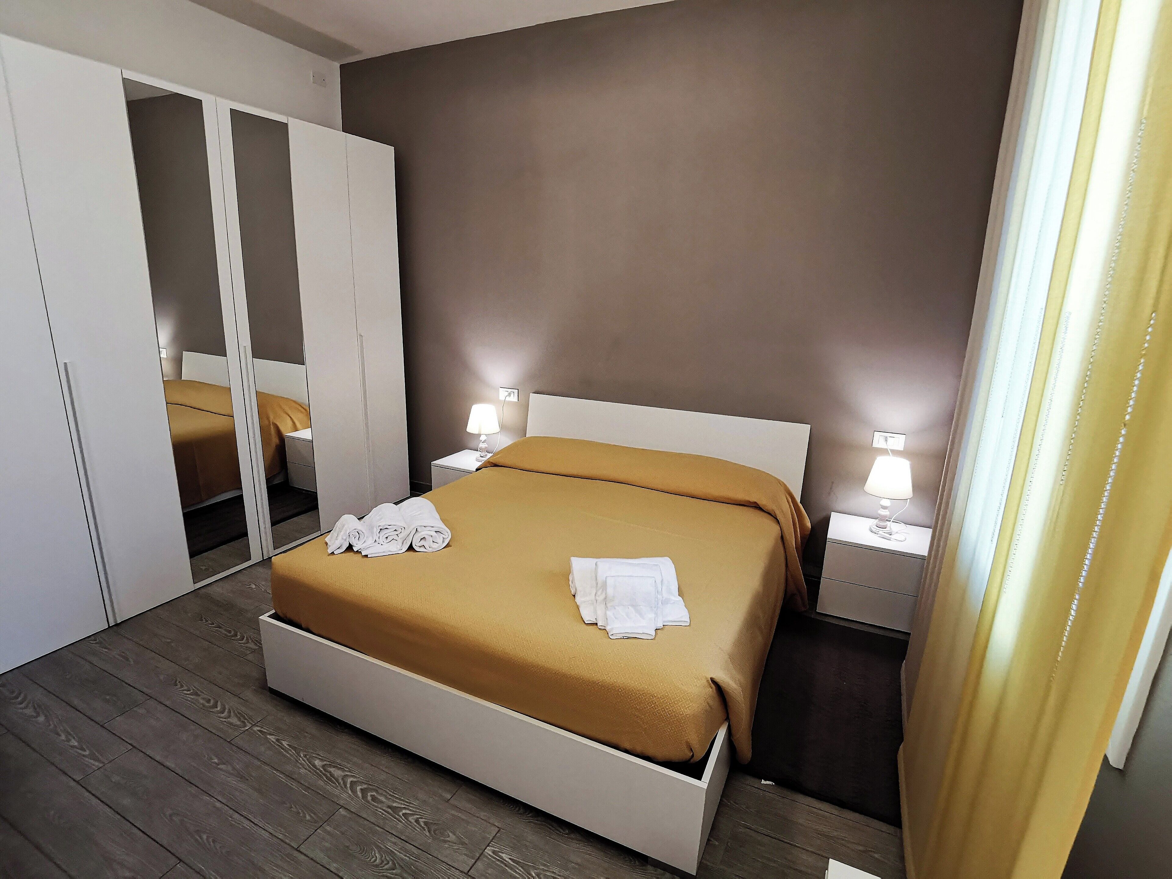 Una camera da letto con un letto, un armadio, un comodino e uno specchio.