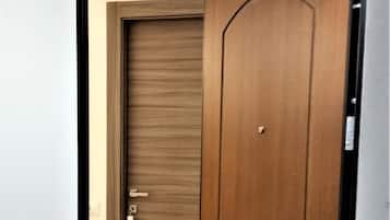 Una puerta de madera cerrada con un picaporte de latón y cerradura, y otra puerta entreabierta con un diseño parecido.