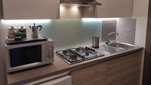 A modern kitchen with a built-in microwave, gas stove, and stainless steel sink. - Casa Belfiore - Martiri di Belfiore 23 (Vicenza)