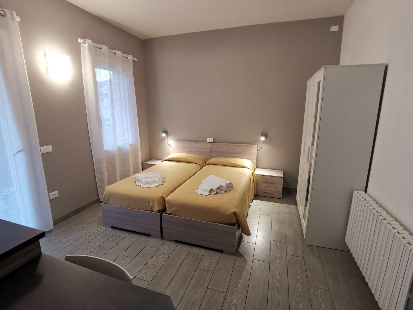 A bedroom with two beds, a desk, and a wardrobe.