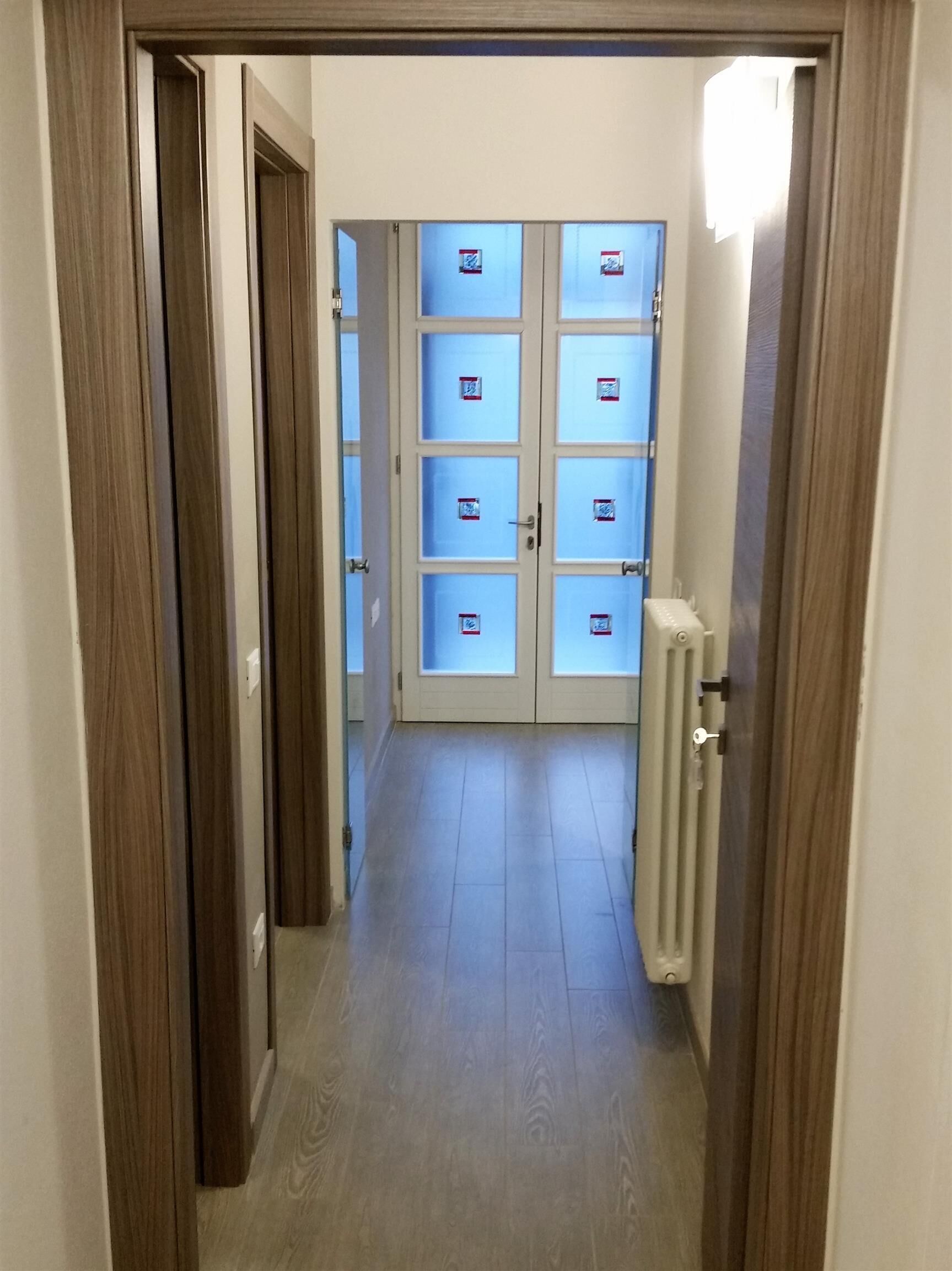 A hallway with a double door leading to a room.