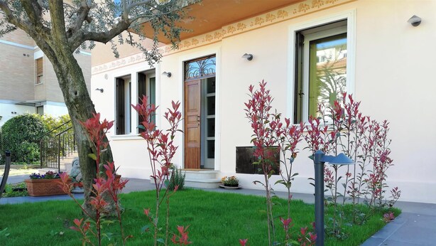 A building with a white facade, a tree in the foreground, and a well-maintained lawn. - Casa Belfiore - Martiri di Belfiore 23 (Vicenza)