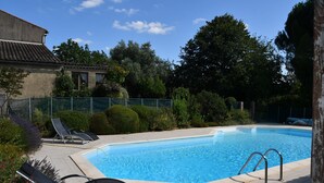 Ein Schwimmbecken mit zwei Liegestühlen und einer Metallleiter.