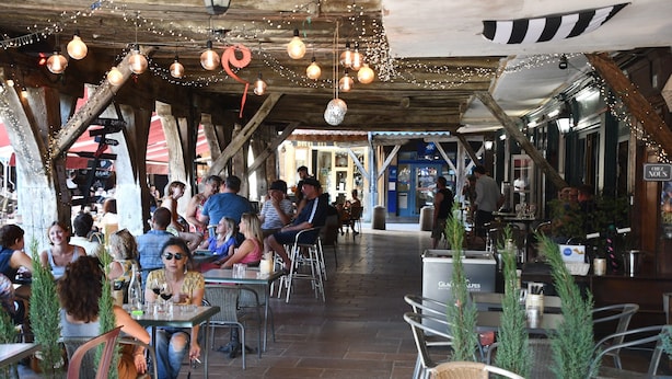 Ein Café im Freien mit rustikalen Holzbalken, Tischen und Stühlen.