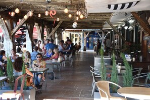 Ein Café im Freien mit rustikalen Holzbalken, Tischen und Stühlen.