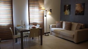 A living room with a dining table, chairs, a sofa, and a floor lamp. - B&B Vescovo Rosso (Cosenza)