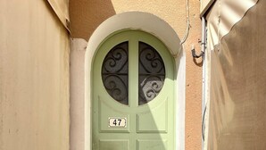 Una puerta verde con una placa con el número 47 y detalles de hierro decorativo.