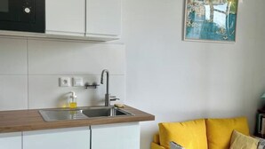 Una cocina con un lavamanos, encimera de madera y un sofá amarillo con un cojín.