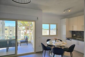 Enjoy a serene outdoor space with a view of the surrounding buildings and a tree from the spacious balcony. The apartment offers a functional kitchen with contemporary cabinetry and a dishwasher.