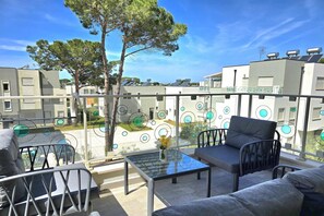 Enjoy the serene view from this balcony with a glass table, comfortable seating, and beautiful flowers.