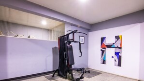 Ein Fitnessraum mit Trainingsgeräten, einem wandmontierten Gestell und einem gerahmten abstrakten Gemälde.