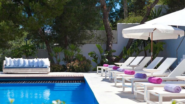 A pool area with lounge chairs and umbrellas, surrounded by greenery. - Villa Bacio - My Rental Homes (San Jose)