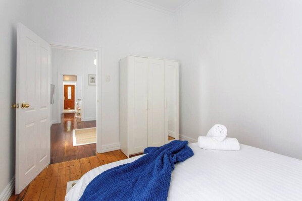 A hotel room with a bed, a wardrobe, and a door leading to another room.