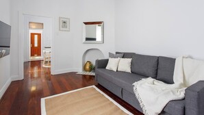 Un salon avec un canapé gris, un tapis blanc et un plancher en bois.