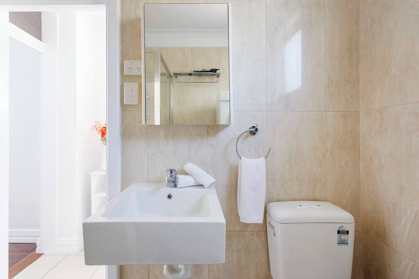 Un bagno con lavandino bianco, uno specchio, un portasciugamani e un water.
