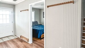 Una habitación con piso de madera, una cama con cubierta azul y una puerta blanca.