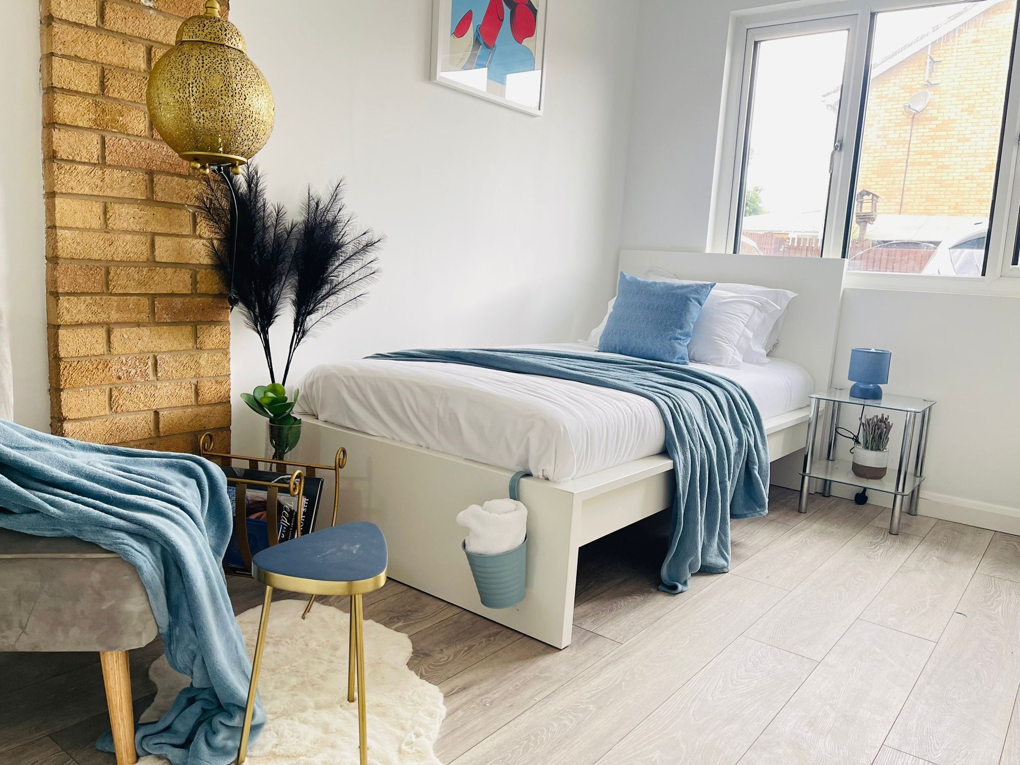 A bedroom with a bed, bedside table, lamp, and a window.