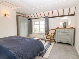 Un dormitorio con cama, cómoda, silla, ventana con cortinas y espejo montado en la pared.