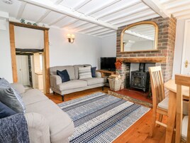 Una sala de estar acogedora con sofá, televisor, chimenea y una mesa de comedor de madera.
