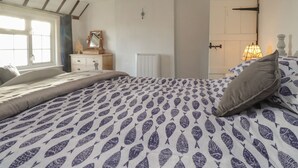 Ein Schlafzimmer mit Bett, Schminktisch, Spiegel, Heizkörper und Fenster.