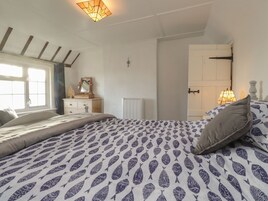 Un dormitorio con cama, cómoda, espejo, radiador y ventana.