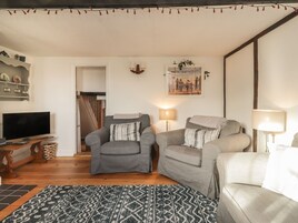 Una sala de estar acogedora con dos sillones grises, un televisor y una alfombra estampada.