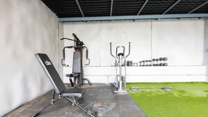 A gym with exercise equipment, a bench, and a wall-mounted dumbbell rack. - Housr 84 Kondapur Near Botanical Garden (Hyderabad)